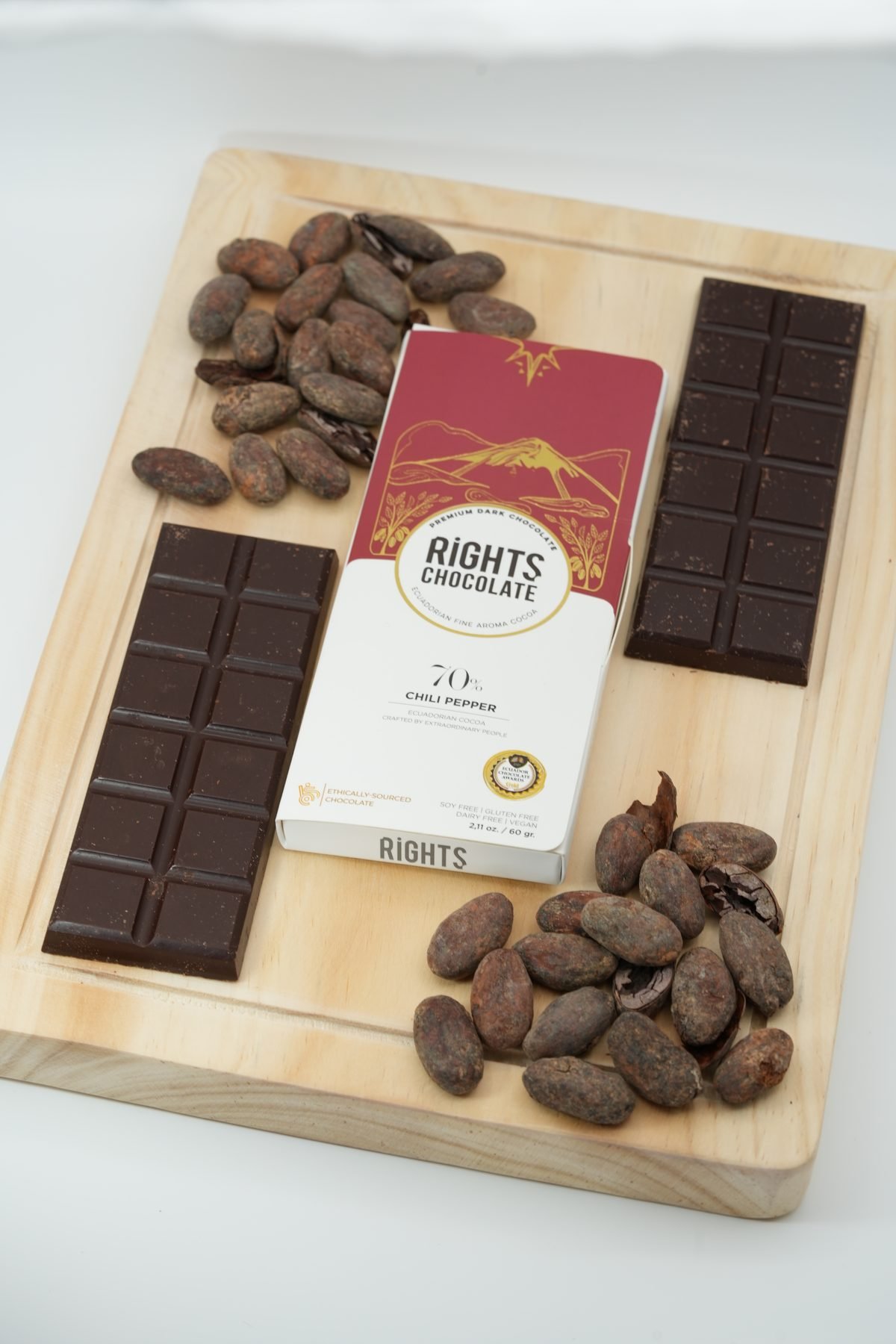 Barra Rights 70 % con trozos de chocolate y granos de cacao sobre tabla de madera