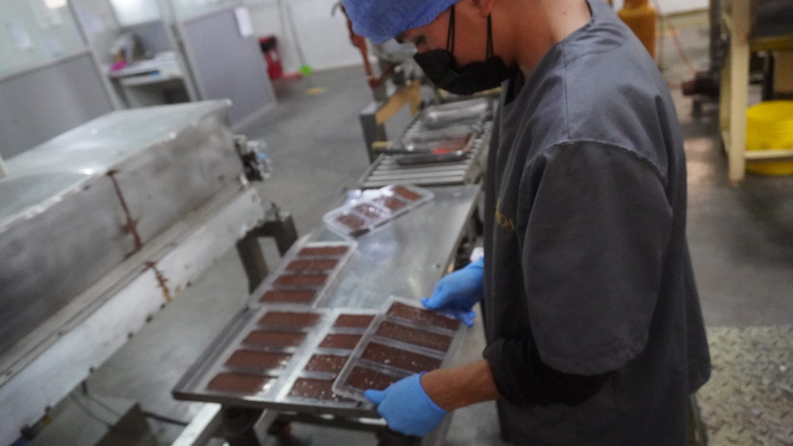 Operario de la planta Rights lleva una bandeja de barras recién moldeadas