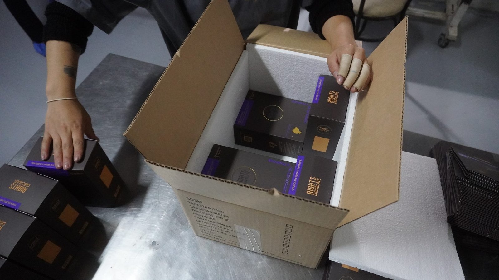 Manos desempacando cajas de chocolate Rights sobre mesa de acero