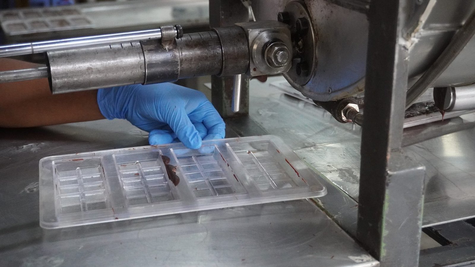 Manos con guantes alisando el chocolate dentro de los moldes de barra